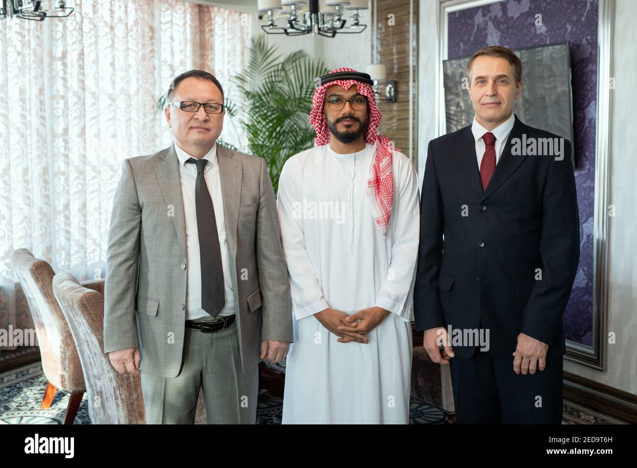 Groupe de partenaires d'affaires ou de délégués ayant réussi à porter des vêtements de coffrage debout dans la rangée devant la caméra contre l'intérieur du bureau ou salle de réunion Banque D'Images