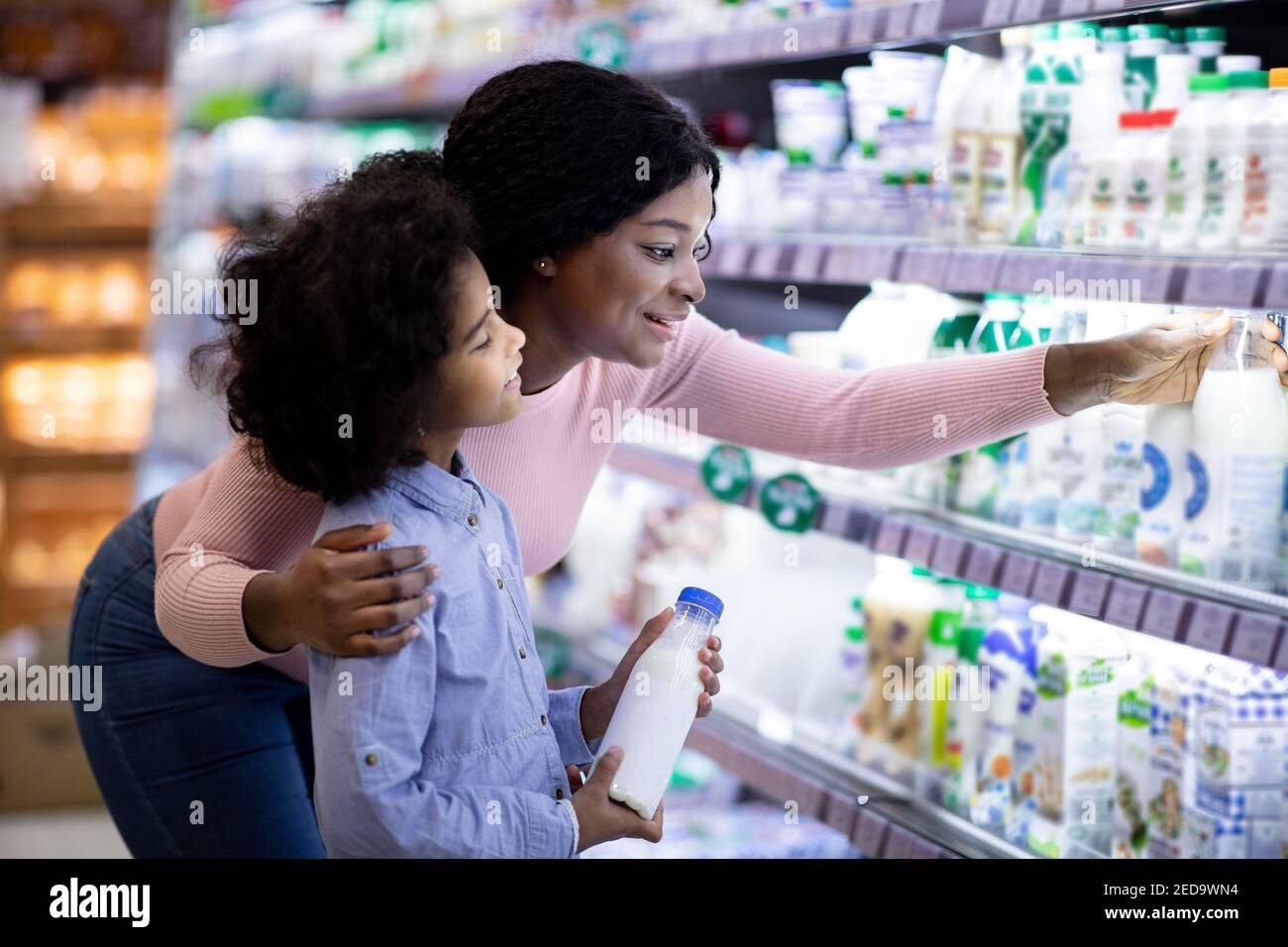 Maman noire positive avec son enfant magasiner pour des produits chez section des produits laitiers du centre commercial Banque D'Images