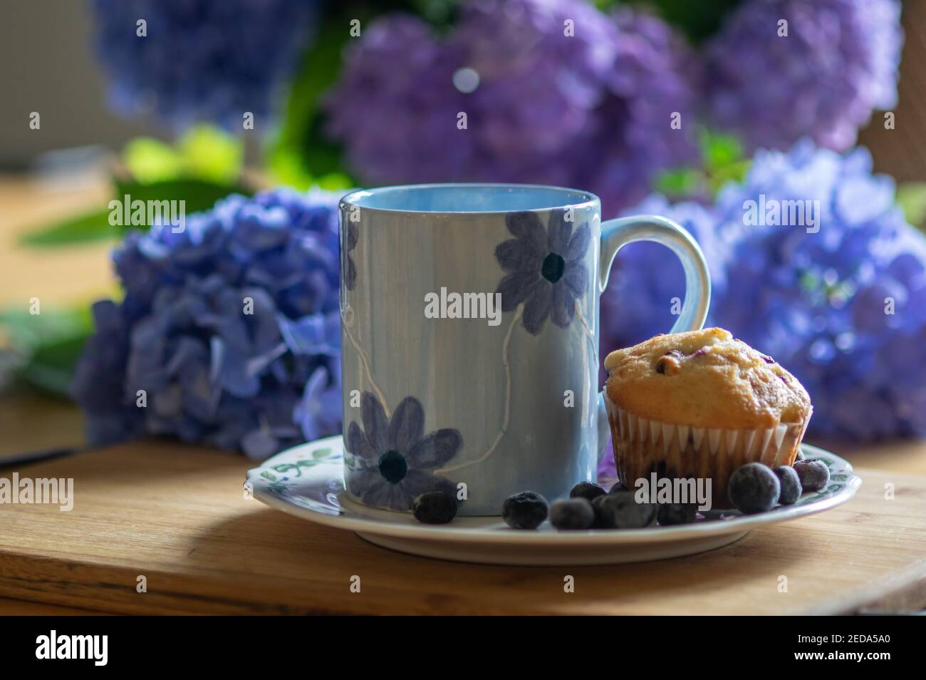 Muffin aux myrtilles sur l'assiette avec tasse à café sur fond de jacinthes Banque D'Images