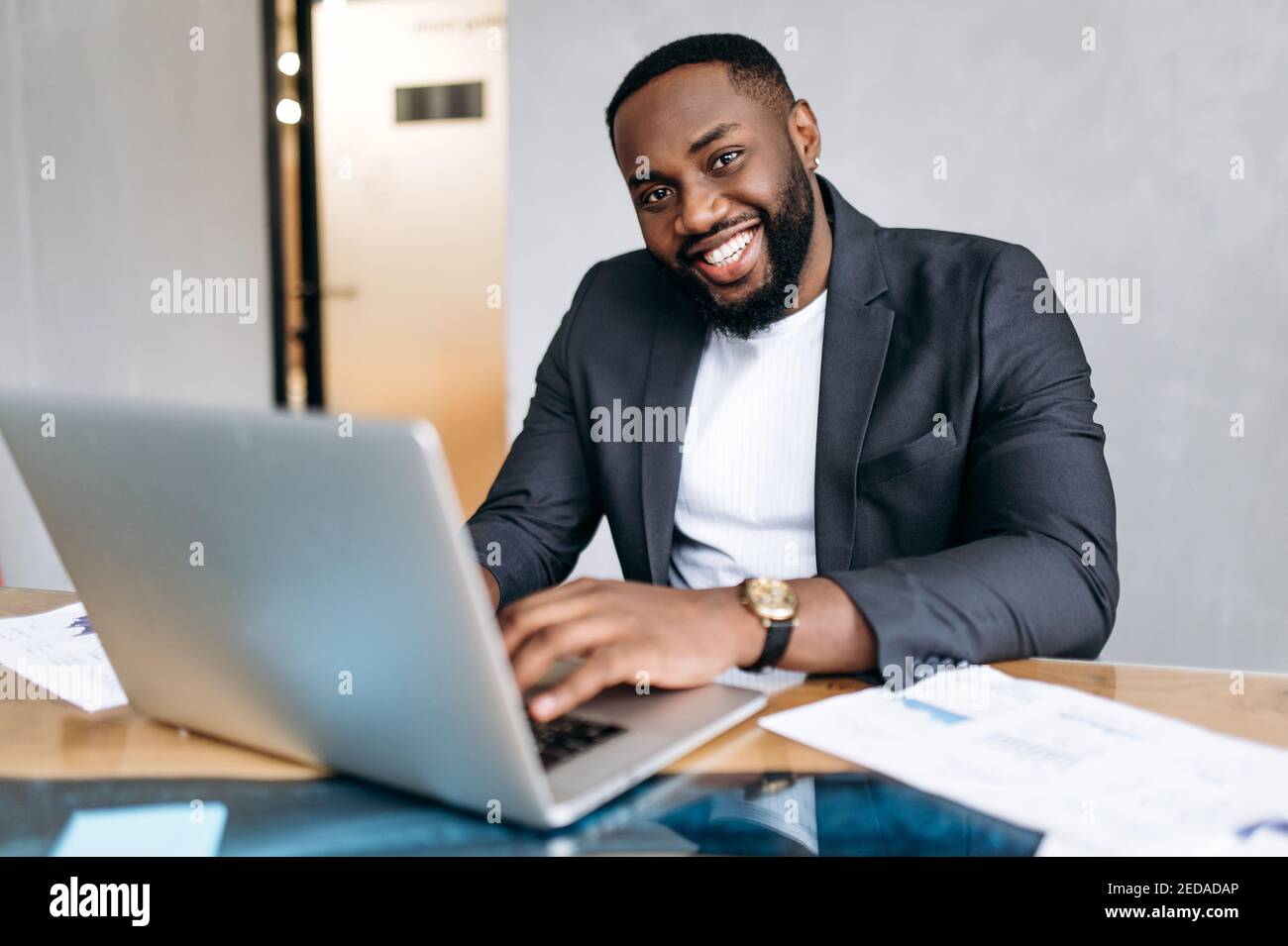 Portrait d'un homme d'affaires afro-américain sur le lieu de travail. Manager homme réussi utilisant un ordinateur portable, travailler sur un nouveau projet ou démarrage. Un employé plein de confiance regarde la caméra, souriant Banque D'Images