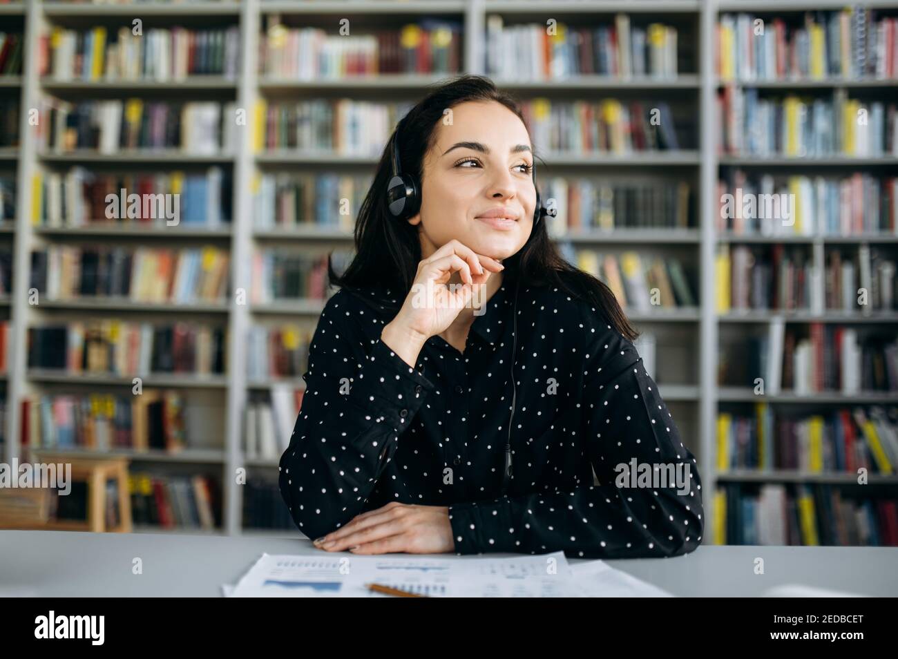 Portrait d'une jeune femme caucasienne satisfaite portant un micro-casque pour travailler en ligne, un opérateur de centre d'appels, un conseiller de client ou un mentor d'affaires, regarde loin avec le sourire Banque D'Images