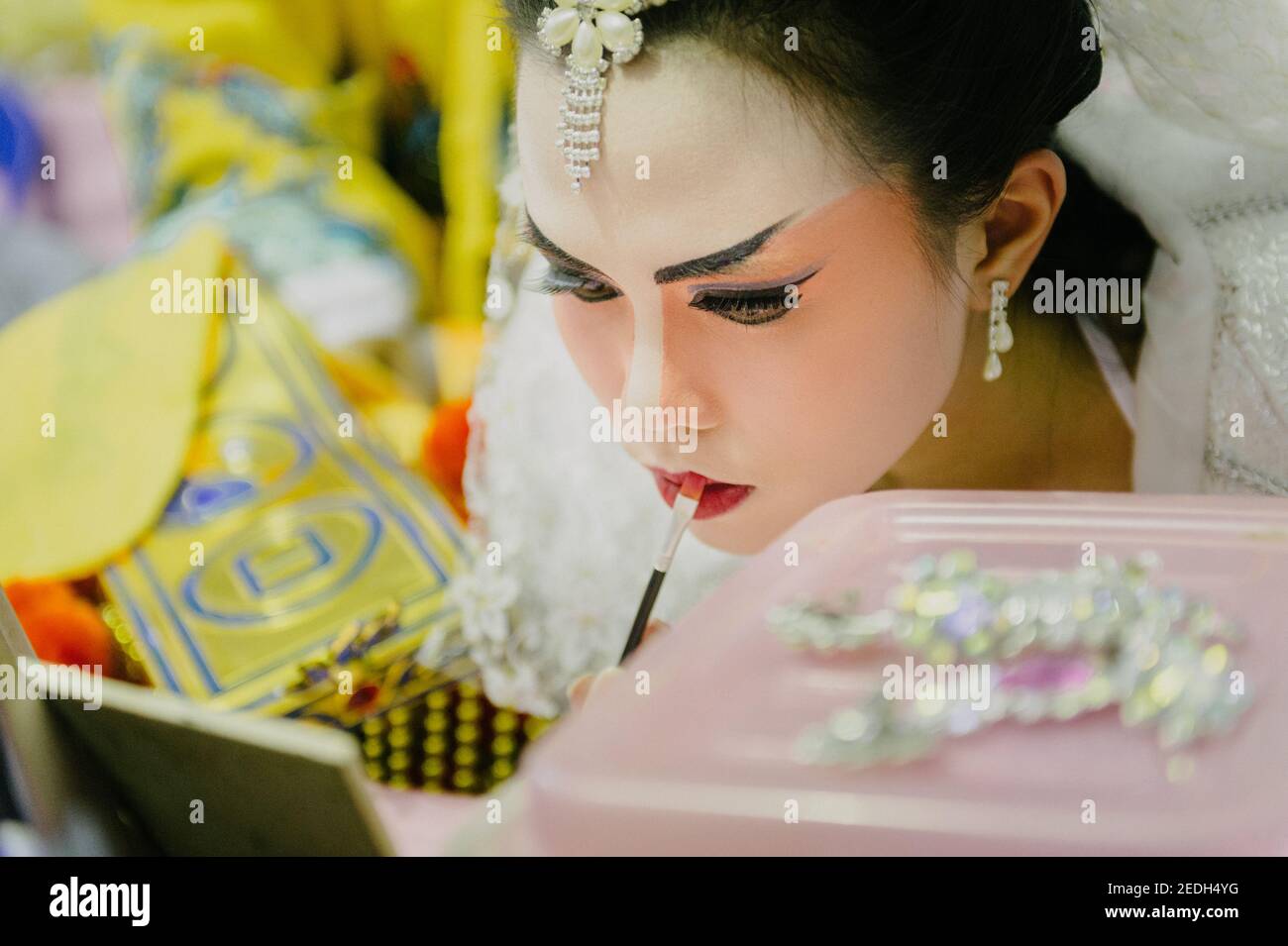 Gros plan d'une jeune femme joueuse d'opéra chinoise dans les coulisses. Elle met son maquillage avant de passer sur scène. Banque D'Images