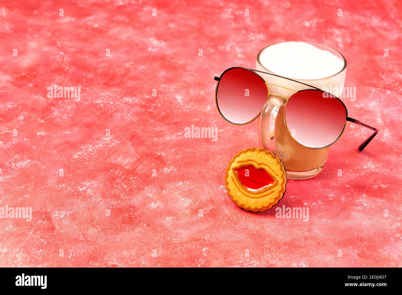 Composition amusante composée d'un verre de cappuccino, de lunettes de soleil et d'un biscuit avec des lèvres de gelée sur fond rose. Banque D'Images