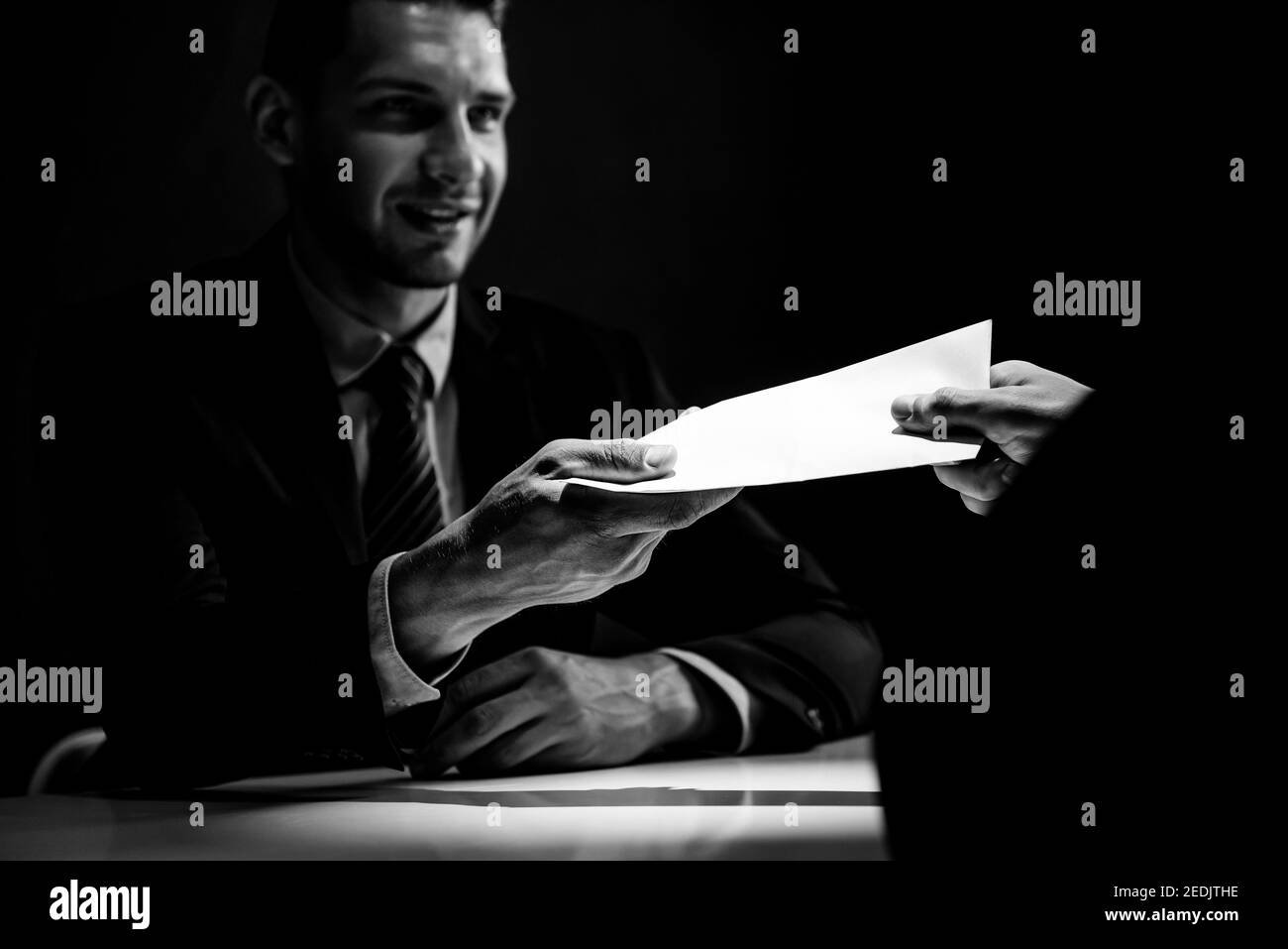 Homme d'affaires donnant de l'argent de pot-de-vin dans l'enveloppe pour s'associer dans une escroquerie de corruption, noir et blanc Banque D'Images