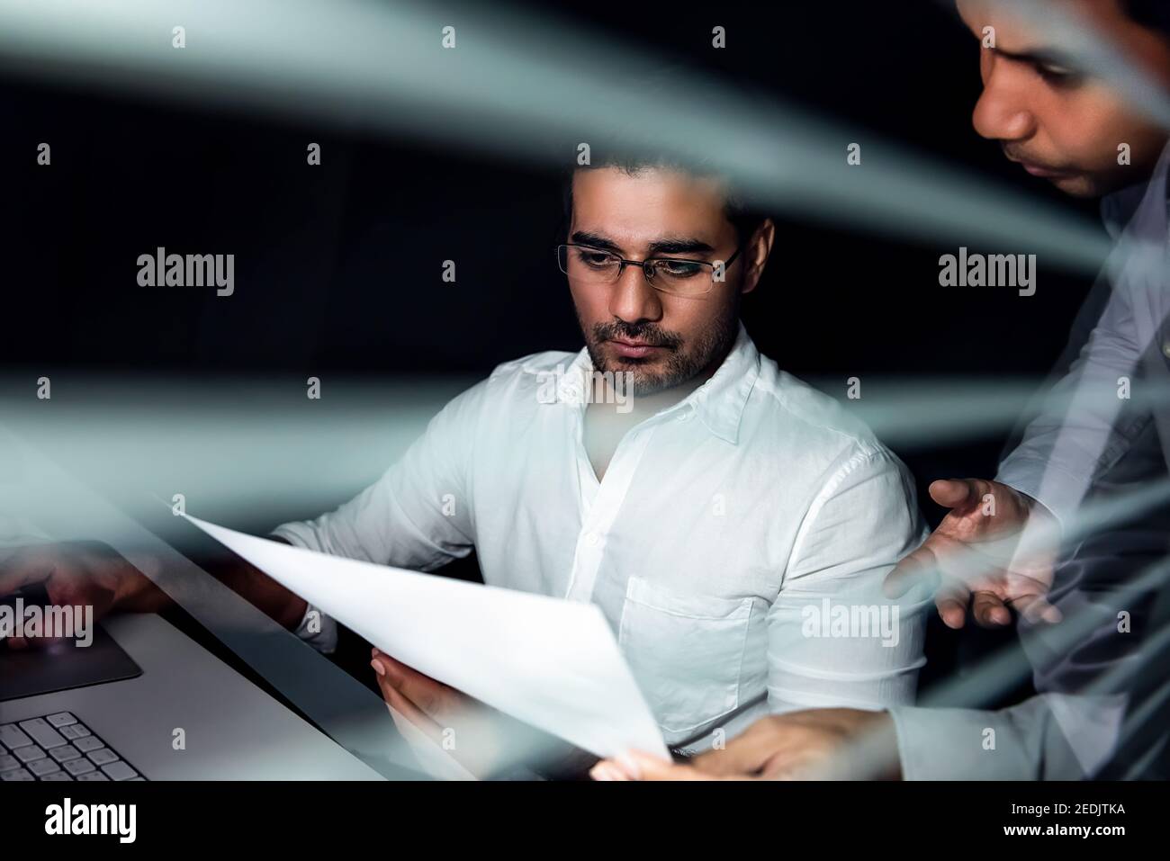 Équipe d'hommes d'affaires asiatiques travaillant de nuit discutant du projet dans le bureau derrière la cloison en verre Banque D'Images
