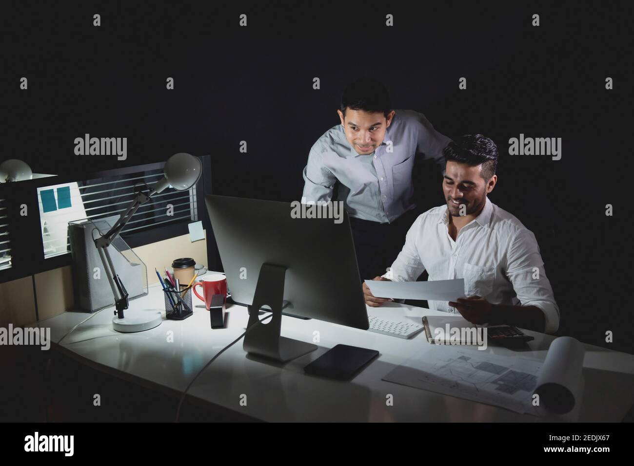 L'équipe d'architectes asiatiques qui reste tard dans la nuit dans les discussions au bureau projeter à la table Banque D'Images