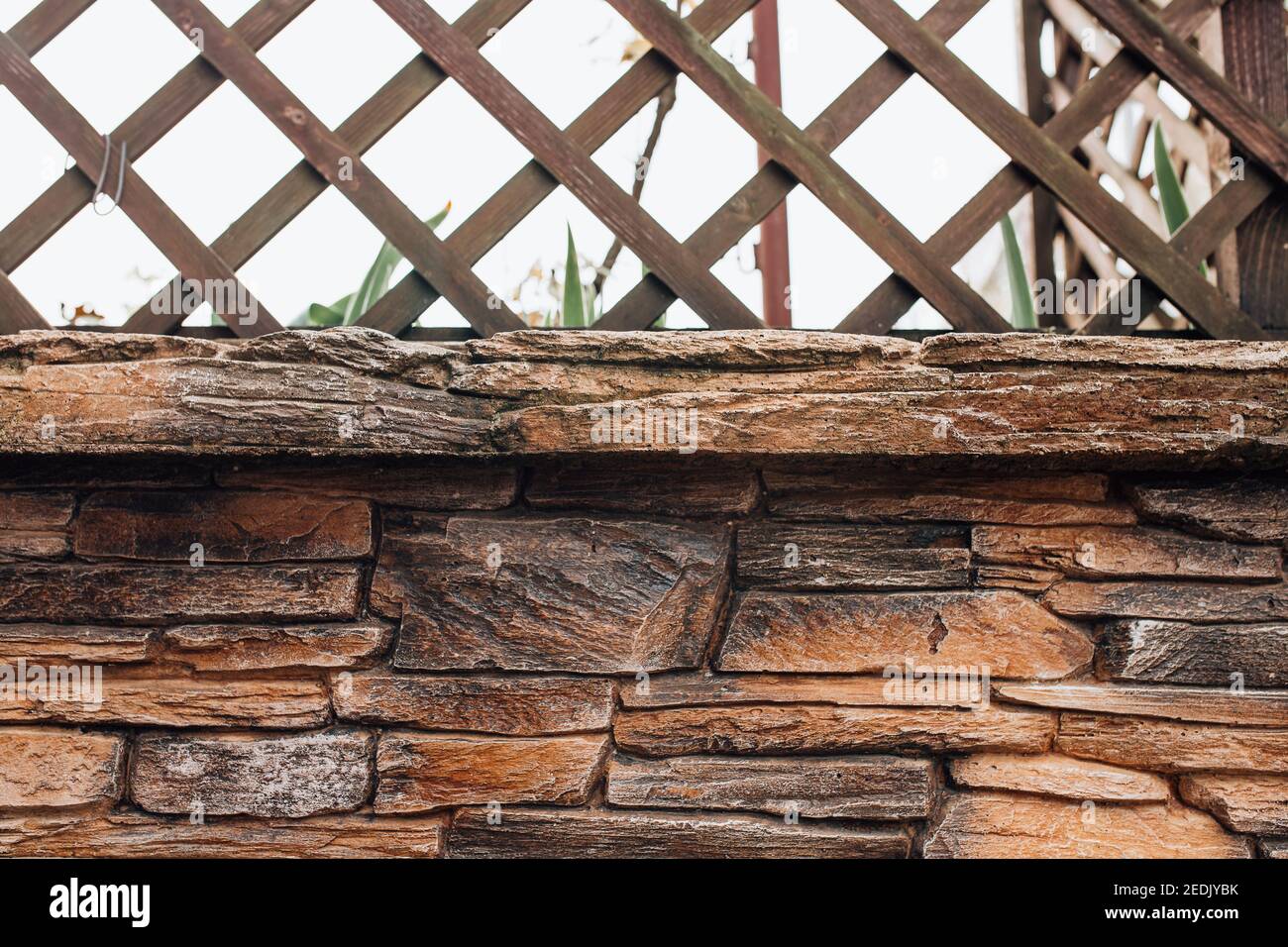 Mur en pierre avec une pergola en bois sur le dessus - jardin clôture