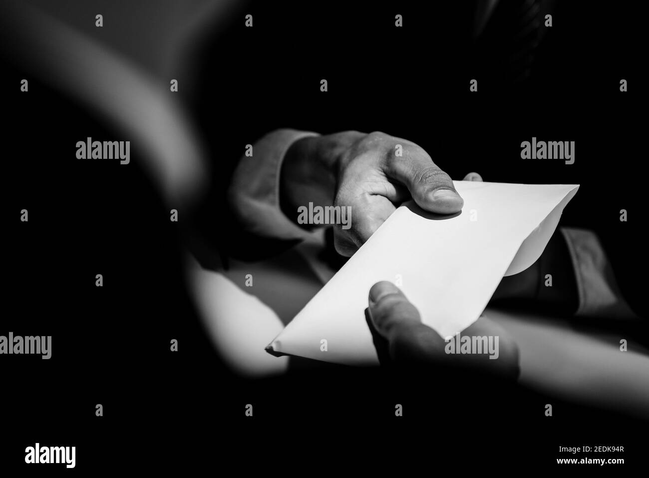 Homme d'affaires donnant de l'argent de pot-de-vin dans l'enveloppe à l'associé dedans une escroquerie de corruption aux tons noir et blanc Banque D'Images