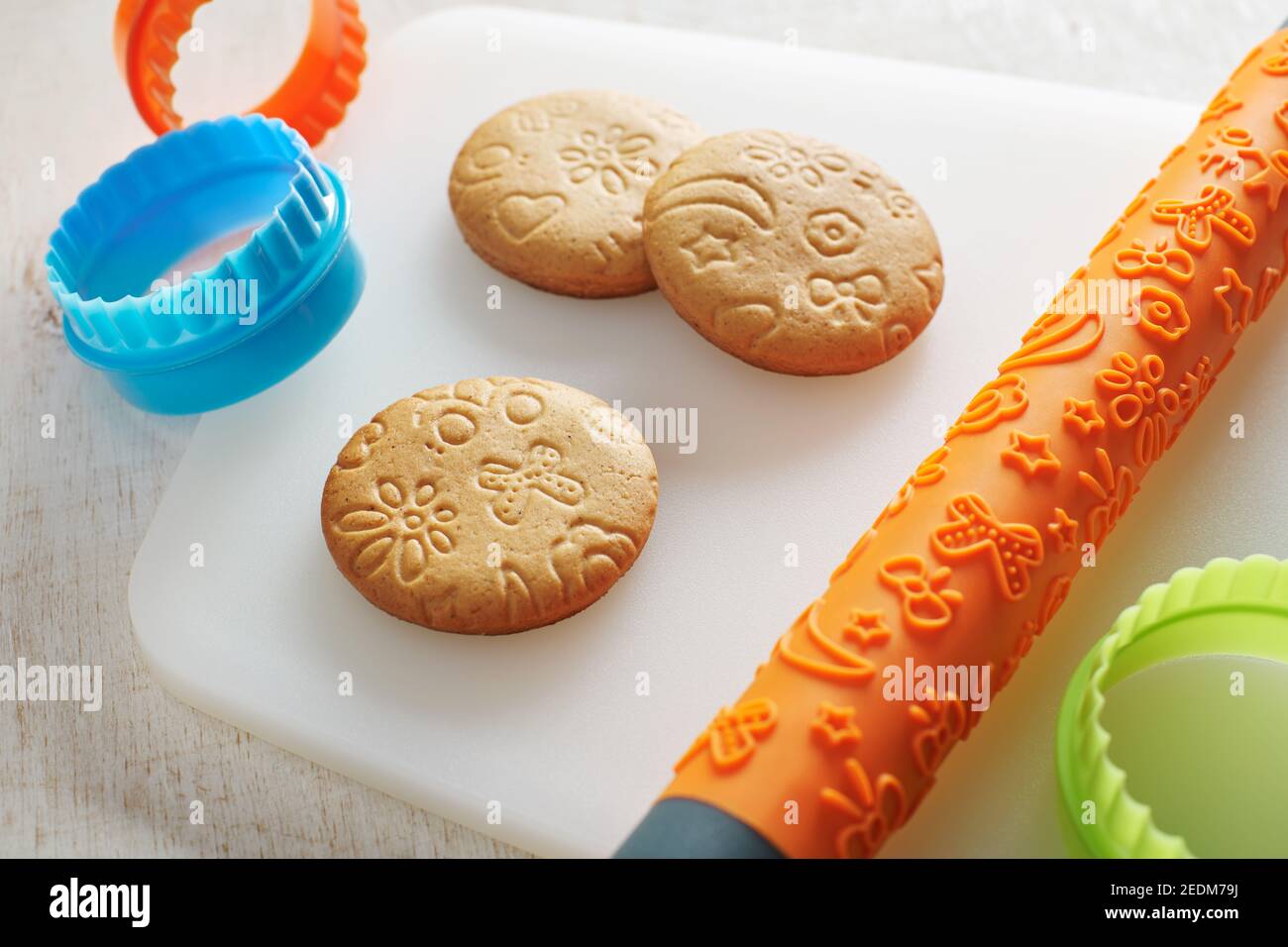 Biscuits, rouleaux à gaufrer et emporte-pièces sur une planche à découper blanche Banque D'Images