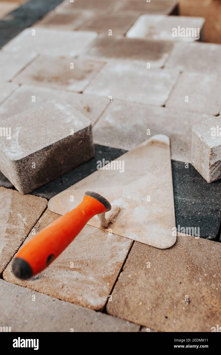 Truelle de briques sur carreaux de pierre de trottoir - pose  professionnelle de pavés Photo Stock - Alamy