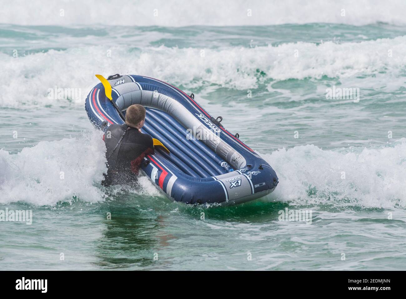 Un holidaymaker portant un canot pneumatique sur Fistral; plage à Newquay en Cornouailles. Banque D'Images