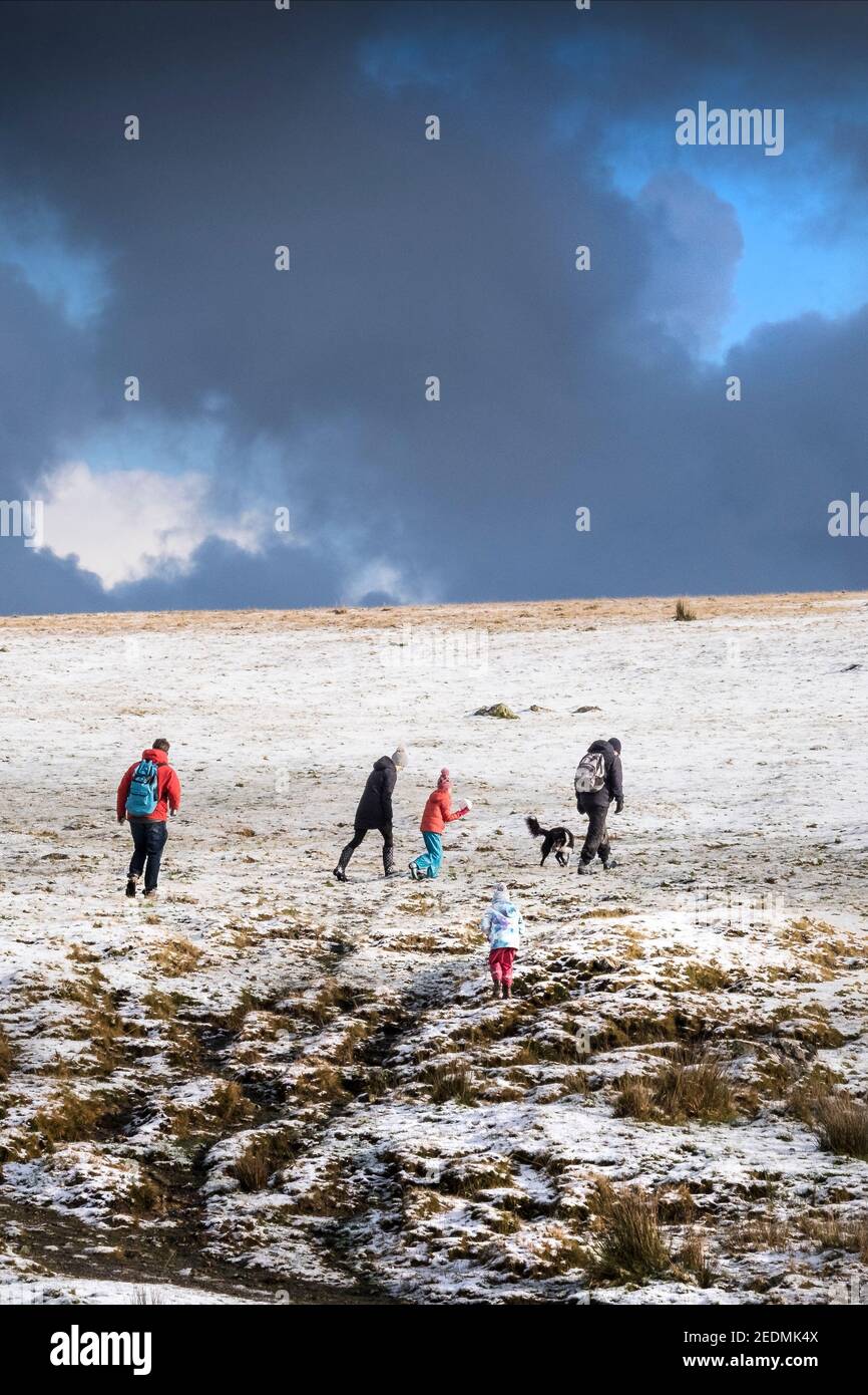 Les gens qui apprécient la marche dans la neige sur la sauvage sauvage Rough Tor sur Bodmin Moor dans les Cornouailles. Banque D'Images