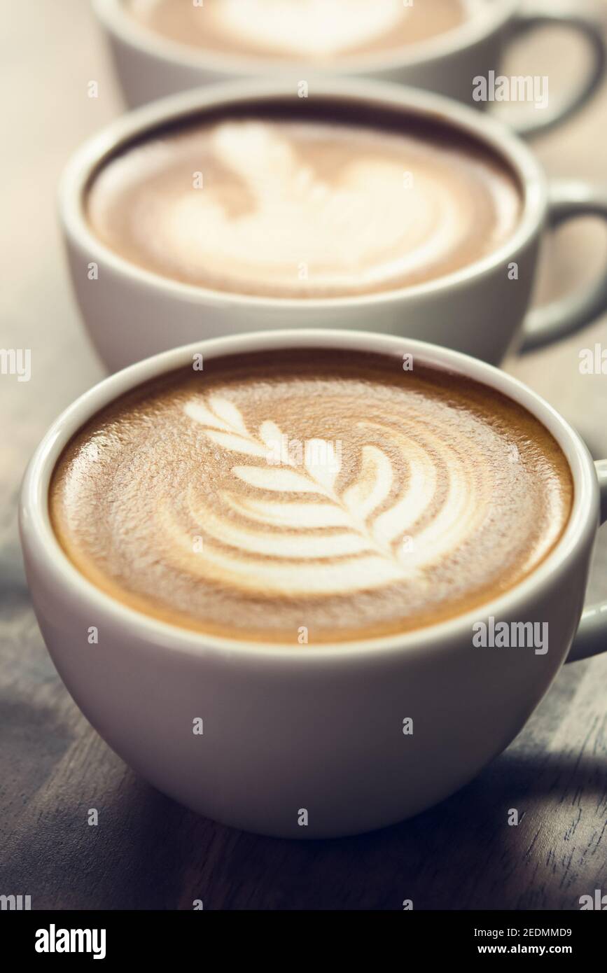 Gros plan sur le magnifique café artistique rosetta les tasses sur table en bois Banque D'Images