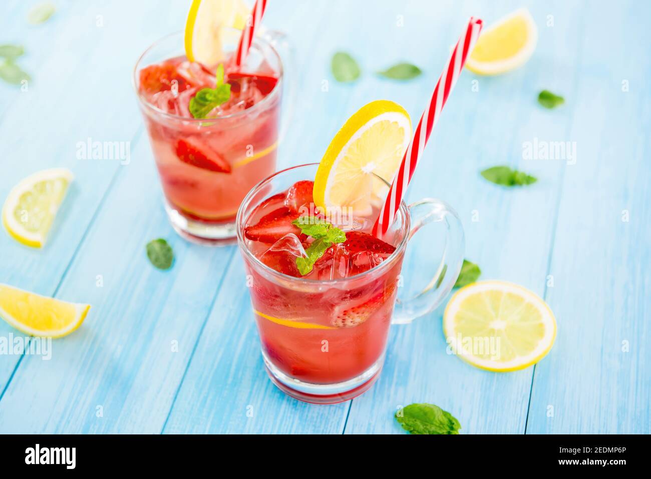 Boissons rafraîchissantes colorées pour l'été, jus de limonade froid aux fraises avec glaçons dans les verres garnis de tranches de citrons frais Banque D'Images