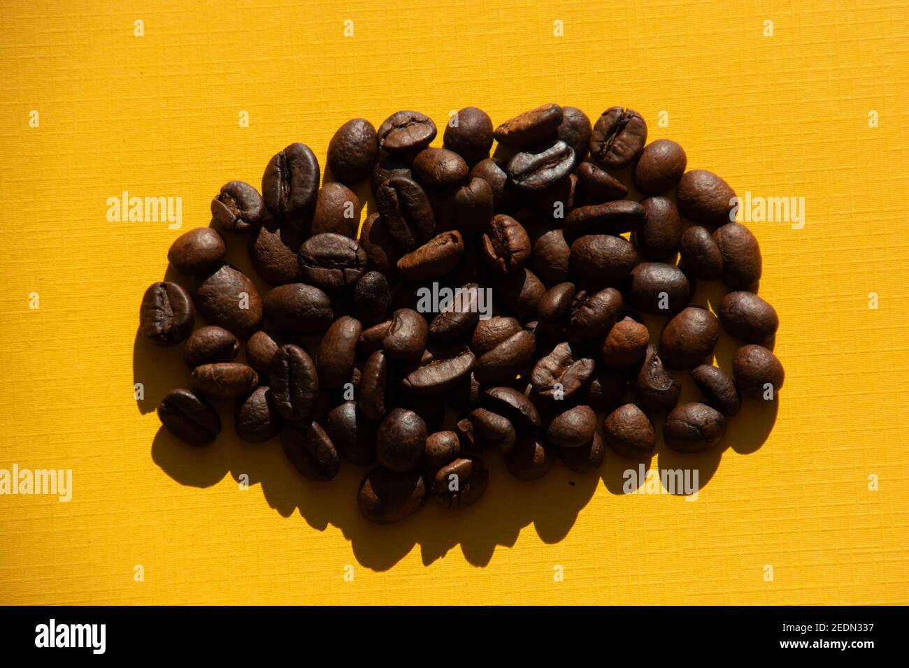 grains de café rôtis foncés sur fond orange coloré thème petit-déjeuner Banque D'Images