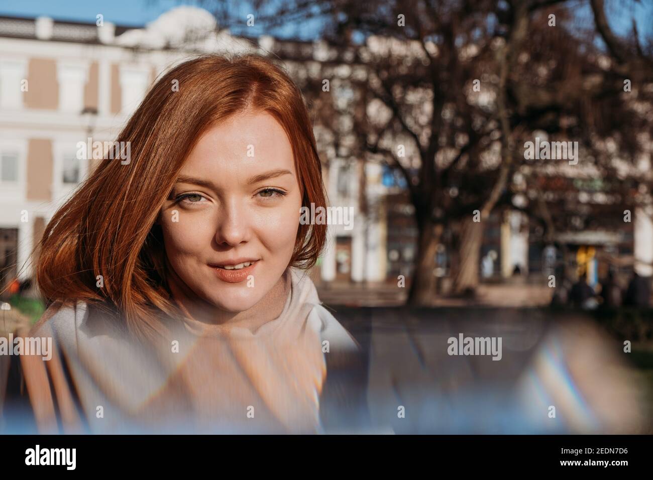 Vie lente en milieu urbain, vie urbaine lente, pleine conscience, profiter du moment, équilibre travail-vie privée. Jeune femme rouge appréciant le soleil et Banque D'Images