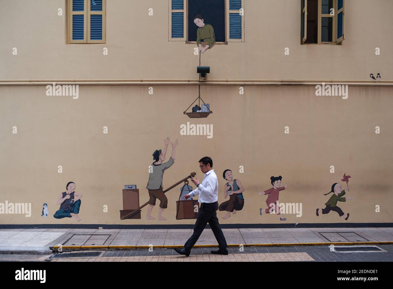 12.04.2019, Singapour, , Singapour - un employé de bureau passe devant une fresque représentant des scènes quotidiennes traditionnelles du passé historique de Singapour dans le Banque D'Images 12.04.2019, Singapour, , Singapour - un employé de bureau passe devant une fresque représentant des scènes quotidiennes traditionnelles du passé historique de Singapour dans le Banque D'Images