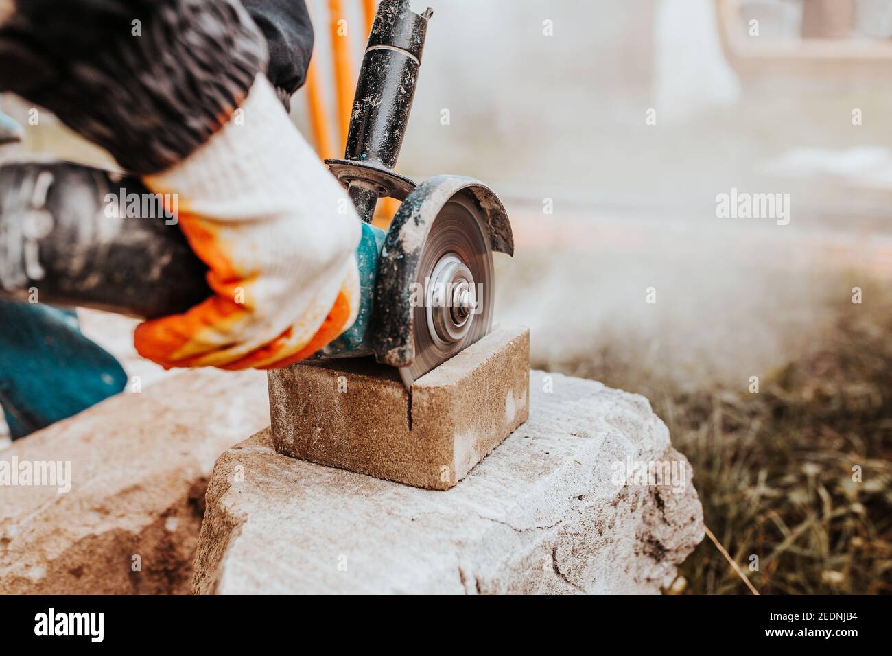 Bricklayer coupe la pierre à l'aide d'une meuleuse angulaire - rapide et sûre - poussière des outils électriques Banque D'Images