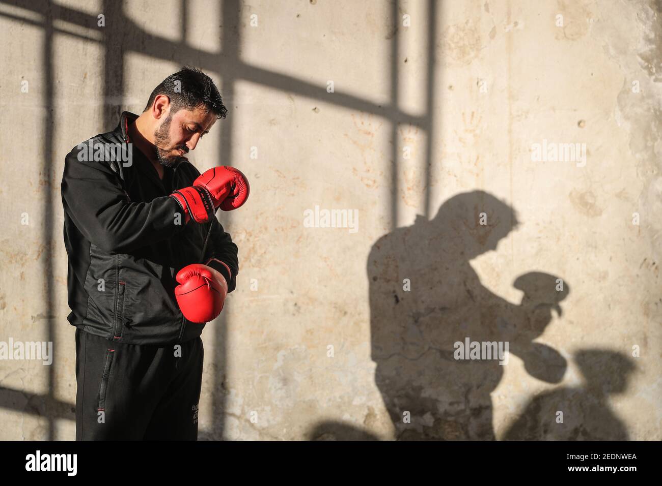 Atareb, Syrie. 14 février 2021. Ahmad Dwara se porte bien avant une séance de formation. Cet homme de 25 ans, qui a été déplacé à l'intérieur du pays, a connu un début de carrière prometteur en tant que boxeur, en remportant les championnats syriens en 2009 et en compétition internationale aux championnats du monde de boxe en 2011. Le début de la guerre civile syrienne il y a dix ans a empêché une carrière professionnelle. Aujourd'hui, le chauffeur d'ambulance pratique dans un entrepôt partiellement détruit souvent attirer des enfants de l'entraînement de quartier avec lui. Credit: Aras Alkharboutli/dpa/Alamy Live News Banque D'Images