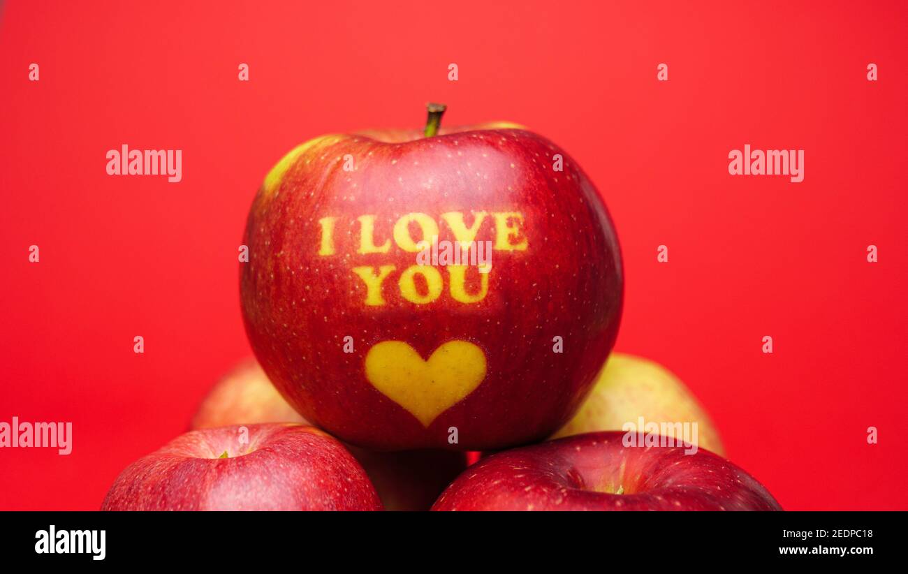 Pomme sur le thème de la Saint-Valentin avec je vous aime message et un symbole de coeur placé sur un fond rouge Banque D'Images