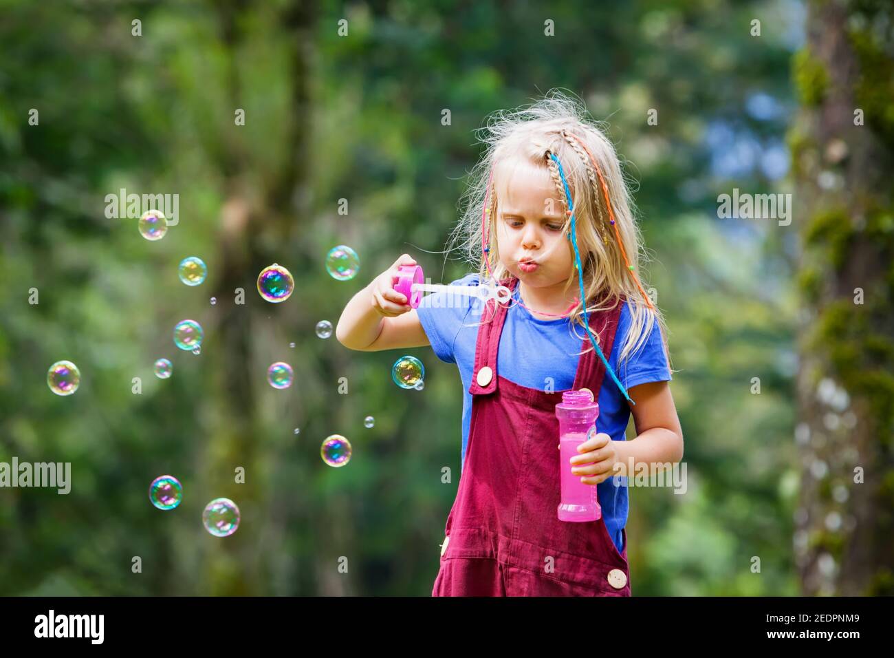 Bonne fille jouant avec des bulles de savon. Enfants actifs qui marchent dans le parc. Style de vie en famille, activités de plein-temps, vacances d'été avec les enfants. Banque D'Images