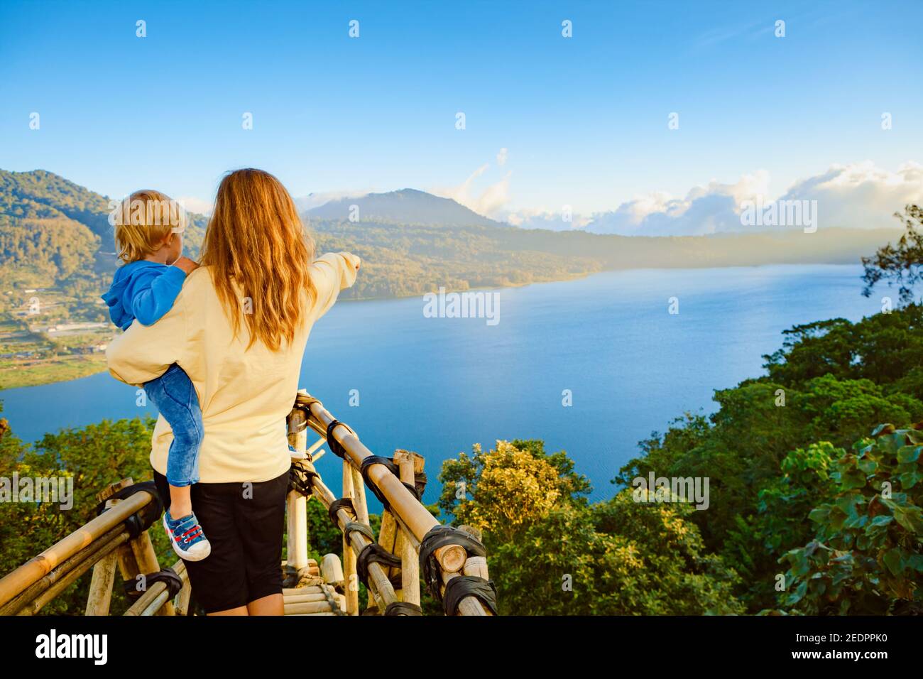 Vacances d'été en famille. La jeune mère avec son bébé se trouve au balcon sur la falaise. Un enfant heureux regarde la vue incroyable sur la jungle tropicale. Le lac de Buyan est pop Banque D'Images