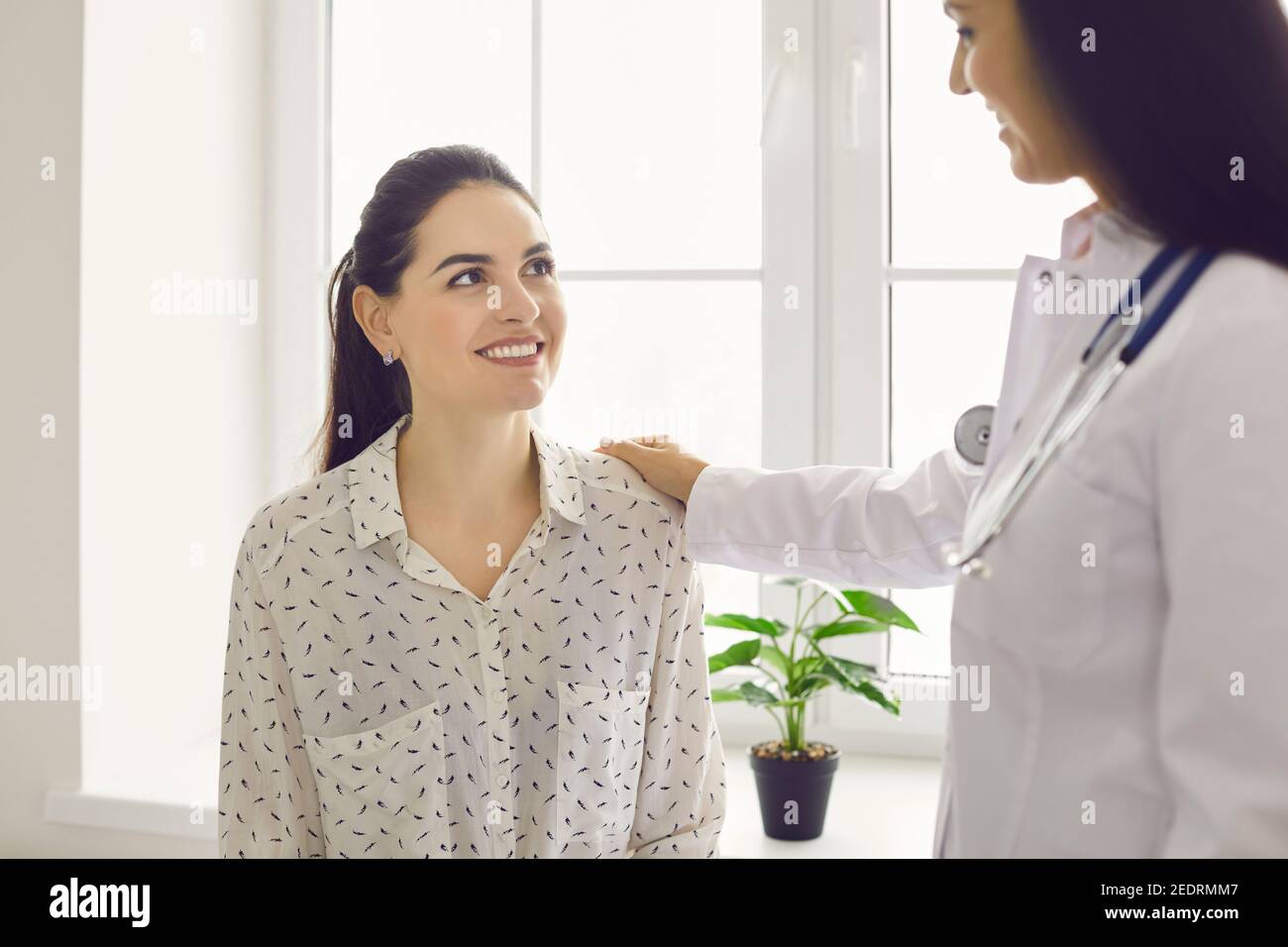 Bonne belle jeune femme regardant son médecin amical pendant visite à l'hôpital Banque D'Images