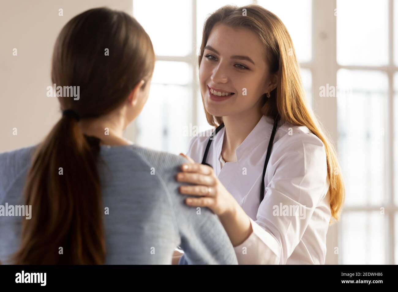 Une jeune infirmière souriante nous dit de bonnes nouvelles sur les résultats des traitements de santé. Banque D'Images