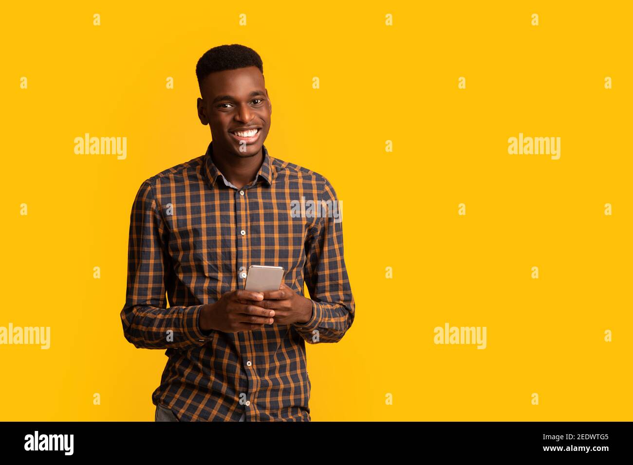 Portrait d'un homme noir heureux avec un smartphone dans les mains souriant à l'appareil photo Banque D'Images