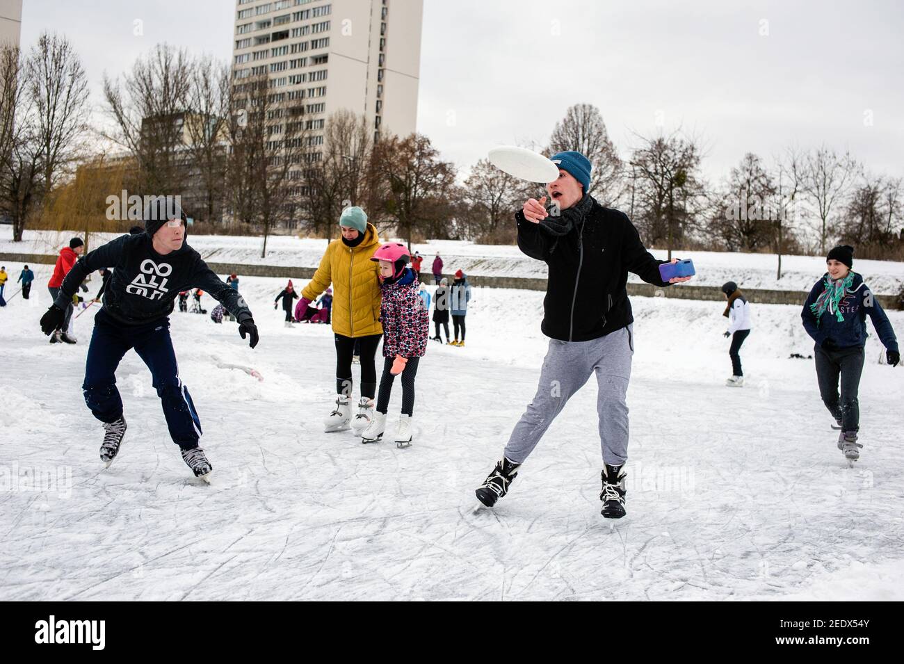 En hiver, les jeunes jouent avec les Frisbee tout en patinant sur un lac gelé. Comme il s'agit de l'hiver le plus froid en Pologne depuis un an et que les températures sont même inférieures à moins 20 degrés dans plusieurs régions, les gens sont fatigués des restrictions du virus de la couronne et se bloquent ainsi en effectuant plusieurs activités hivernales dans les parcs et sur les lacs et les canaux gelés. Banque D'Images