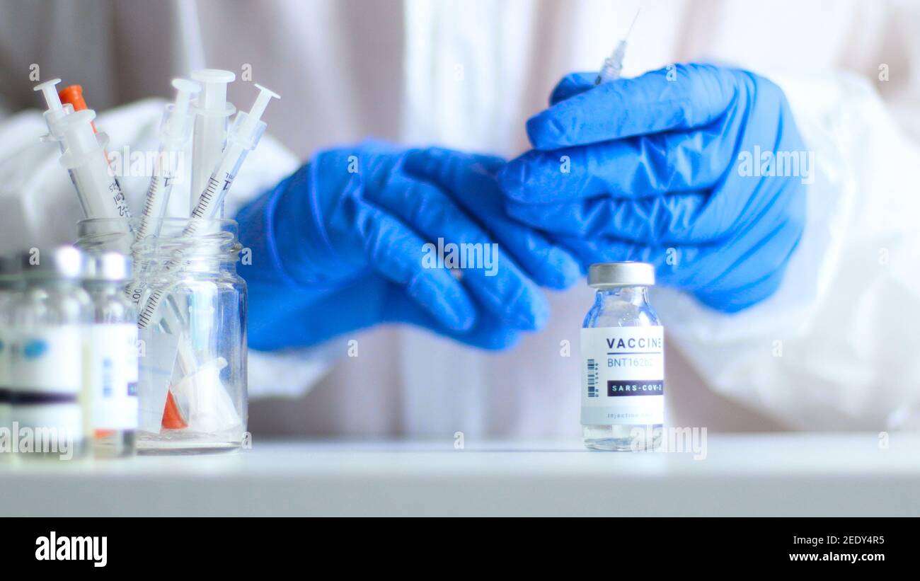 Infirmière ou médecin en uniforme de protection médicale et caoutchouc de latex remplir la seringue de médicaments à partir d'un flacon en verre tout en se préparant au travail pendant une pandémie de coronavirus, de grippe ou de rougeole pour une affiche, une bannière Web, un article ou une publicité Banque D'Images