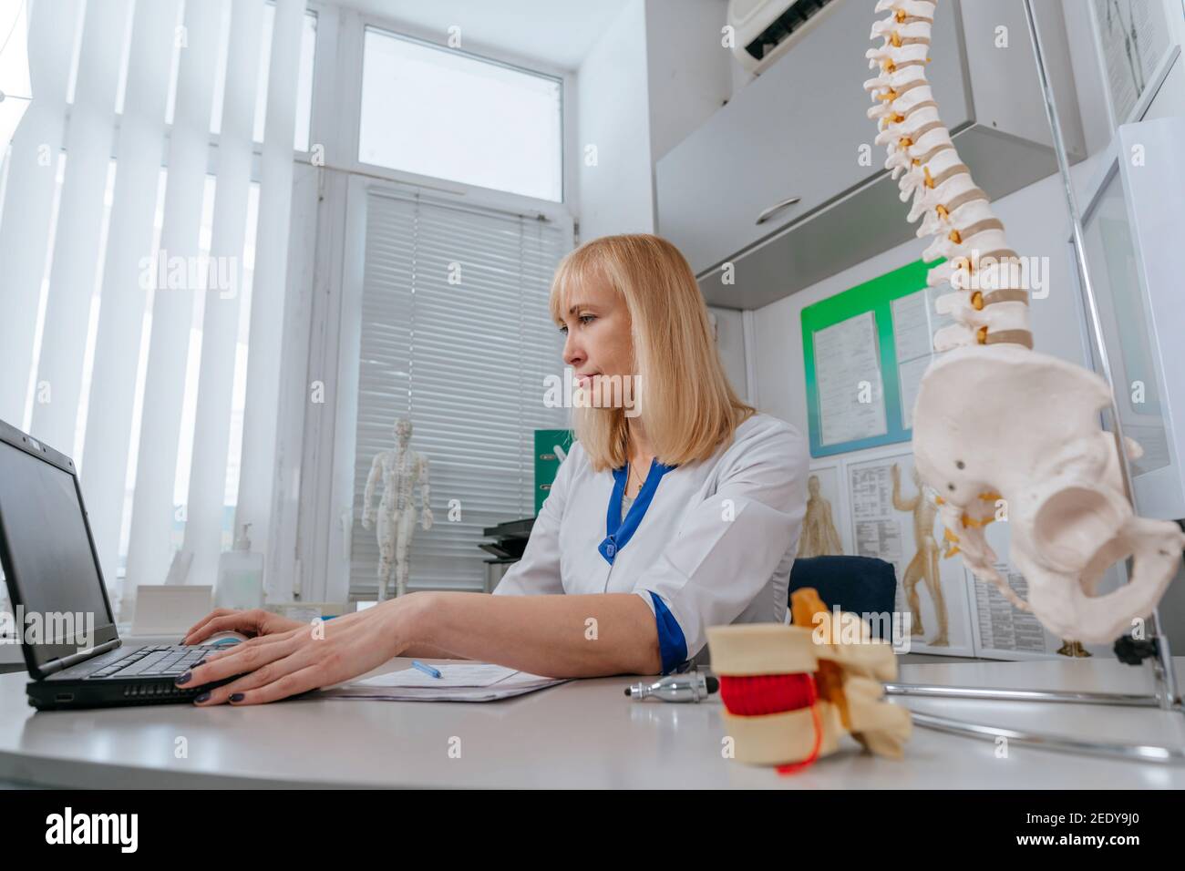 Femme médecin physiothérapeute utilisant un ordinateur portable dans son lieu de travail à l'hôpital Banque D'Images