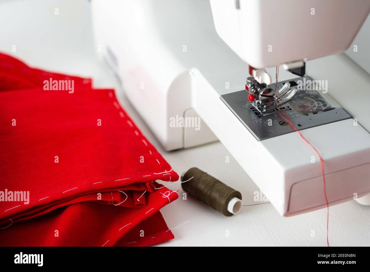 Machine à coudre moderne avec tissu rouge, découpe et couture à la maison, loisirs à la maison et passe-temps Banque D'Images