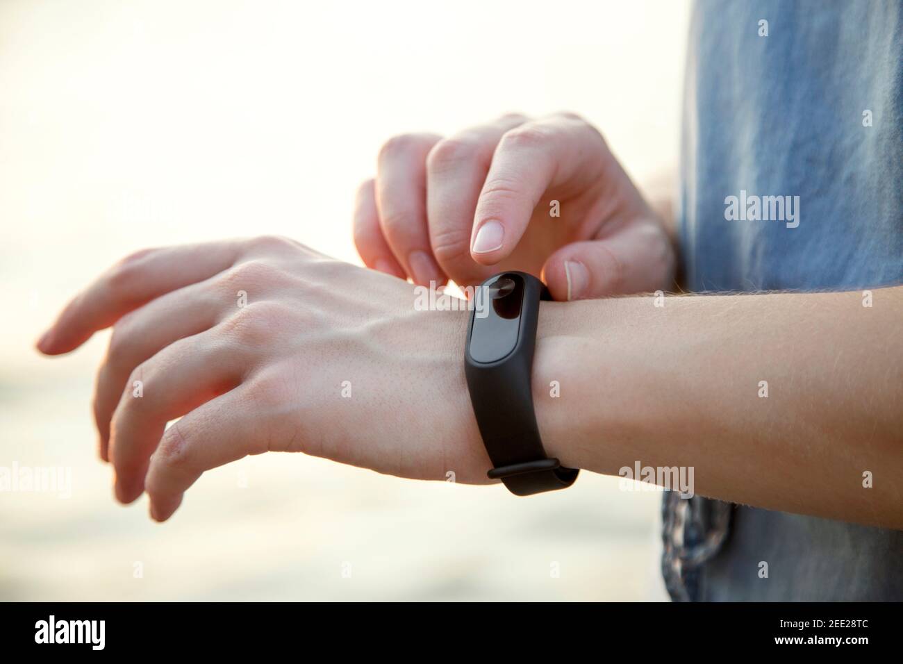 Mains de fille utilisant des montres intelligentes en extérieur. Technologie sans fil tendance avec application mobile pour le fitness. Banque D'Images