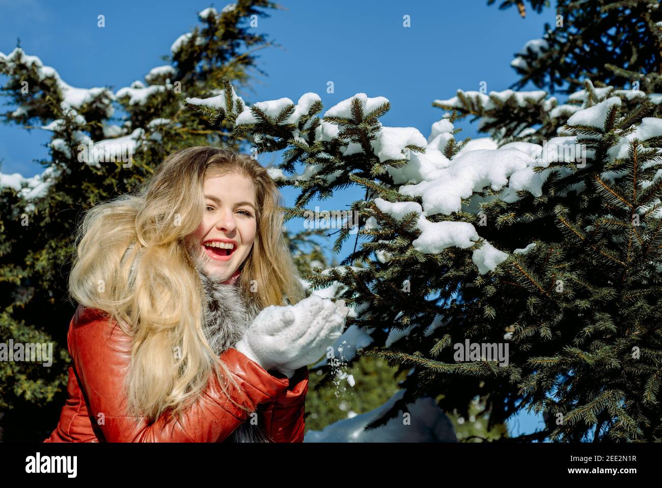 Une fille aux yeux bleus émotionnels soufflant de la neige dans ses mains. Hiver gelé. Banque D'Images