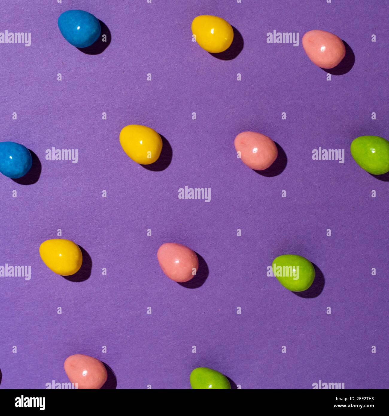 Les bonbons sont disposés sur du papier coloré créant des motifs répétitifs. Série. Banque D'Images