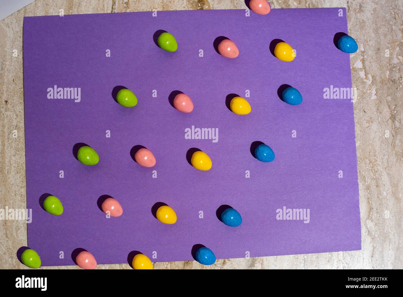 Les bonbons sont disposés sur du papier coloré créant des motifs répétitifs. Série. Banque D'Images