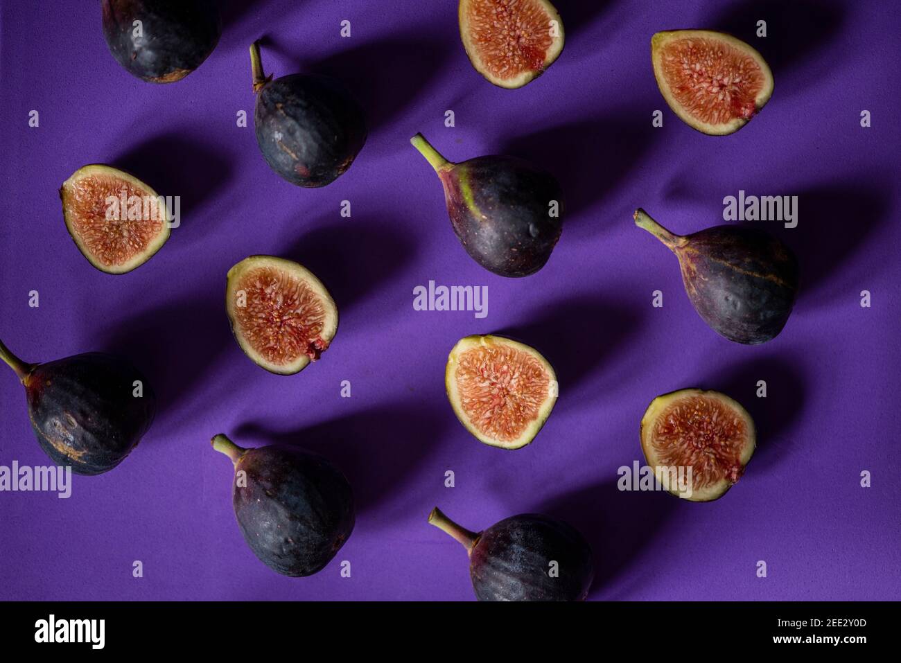Encore plus de vie avec des figues fraîches disposées en répétition sur un fond violet sans couture. Vue de dessus. Banque D'Images