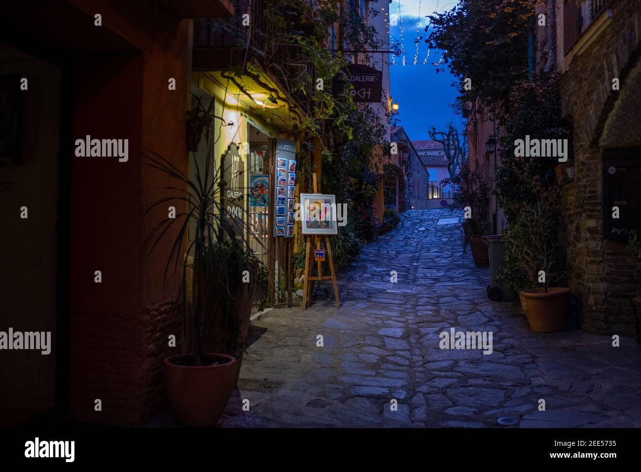 Une boutique d'art de nuit sur une rue pavée vide de la ville touttiste de Collioure, France, prise en décembre soir Banque D'Images