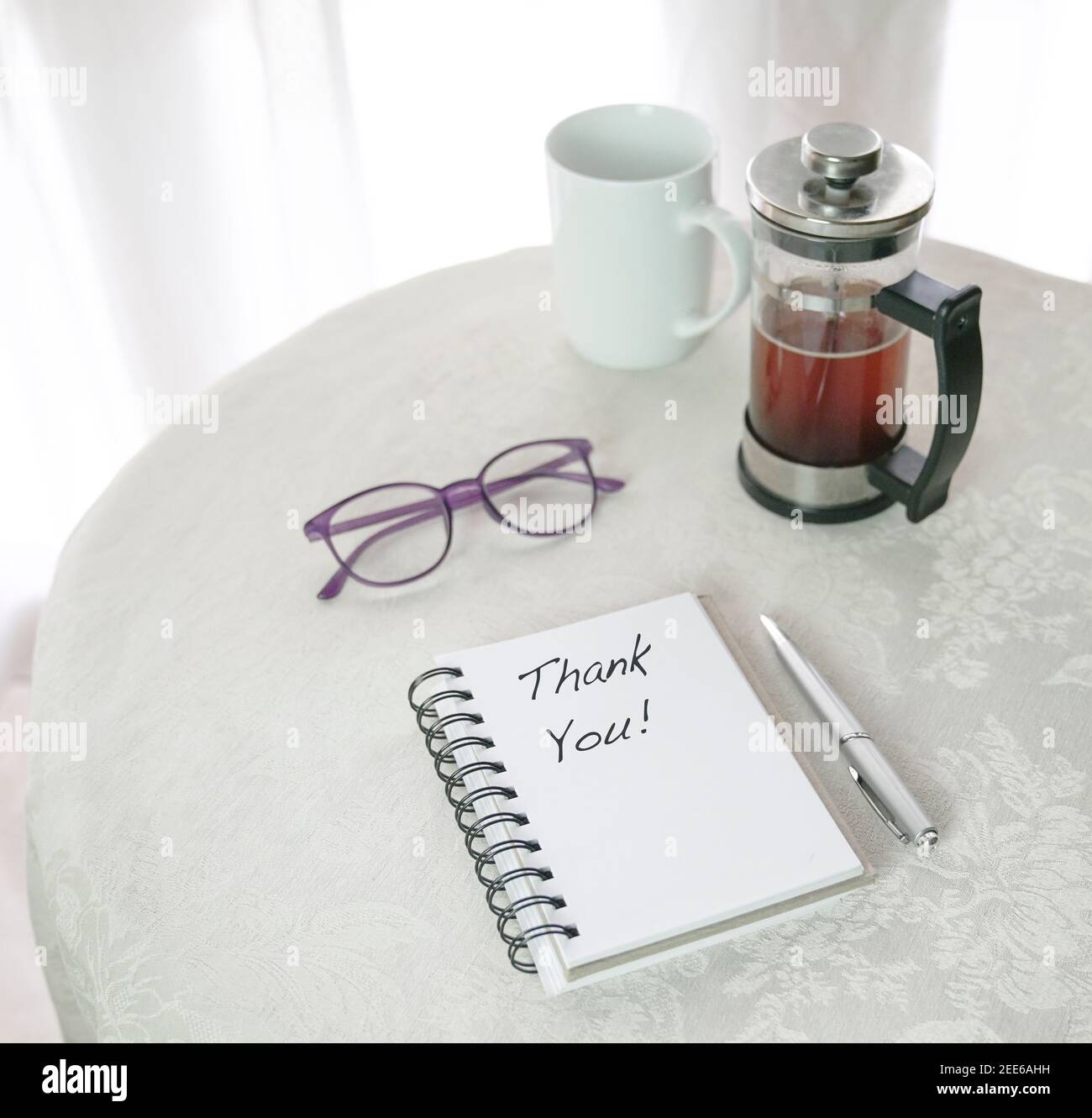 Merci, les mots écrits sur le bloc-notes, à côté de French Press avec café, tasse et lunettes sur la table blanche. Banque D'Images