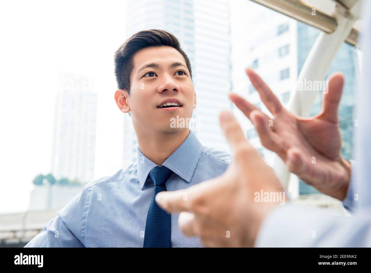 Beau homme d'affaires asiatique chinois discutant avec son partenaire en plein air dans le ville Banque D'Images