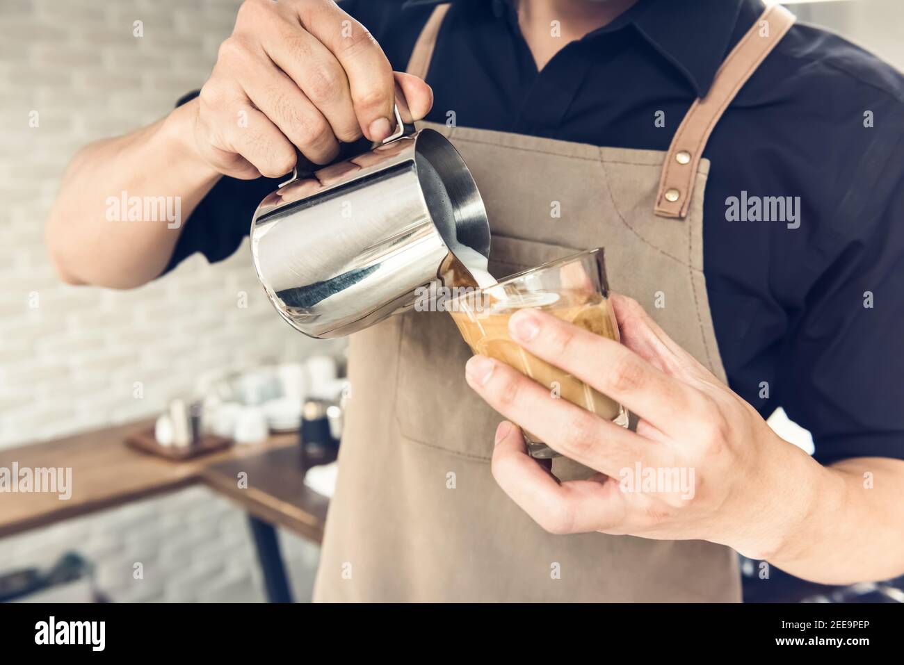 Un barista professionnel verse du lait chaud dans une tasse de café pour préparer un Latte art dans le café Banque D'Images