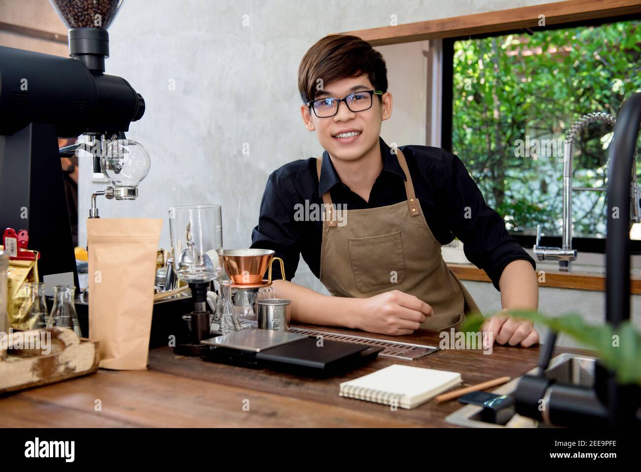 Jeune entrepreneur asiatique assis au comptoir dans son propre café boutique Banque D'Images