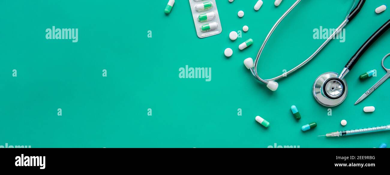 Pilules et équipments médicaux, y compris stéthoscope, seringue et ciseaux à la bordure sur fond de bannière verte, vue du dessus avec espace de copie Banque D'Images