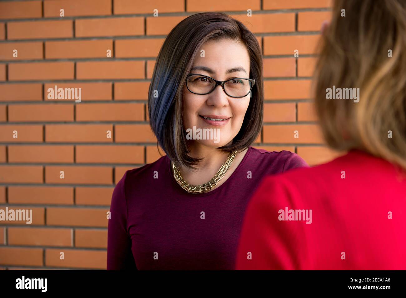 Femme d'affaires asiatique décontractée à l'écoute de son collègue et montrant sa compréhension Banque D'Images