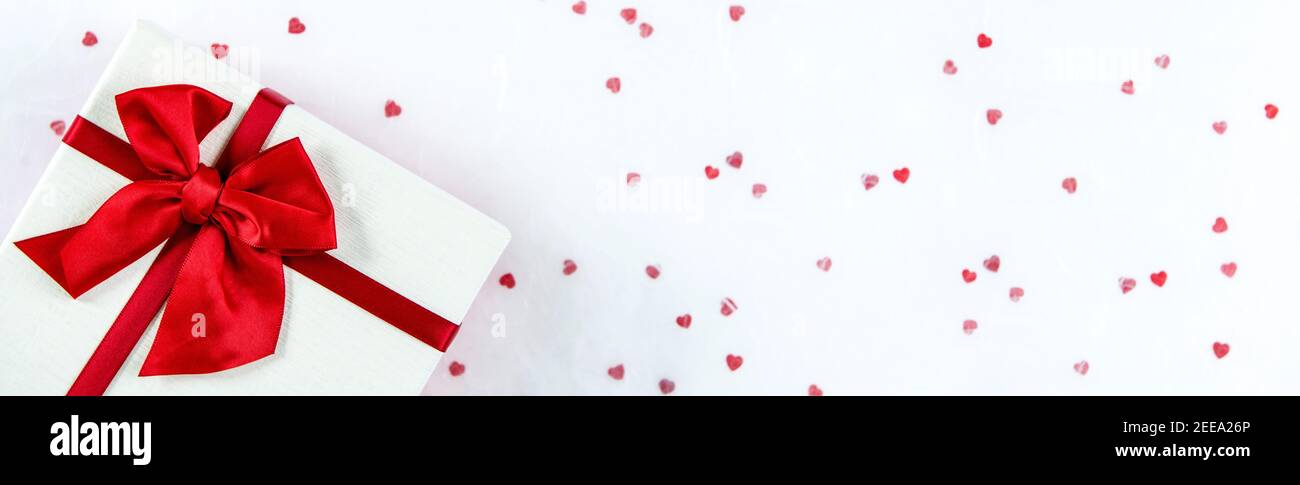 Boîte cadeau de Saint-Valentin ou de mariage sur fond de papier blanc avec motif en forme de coeur rouge, bannière panoramique avec vue de dessus et espace pour les copies Banque D'Images