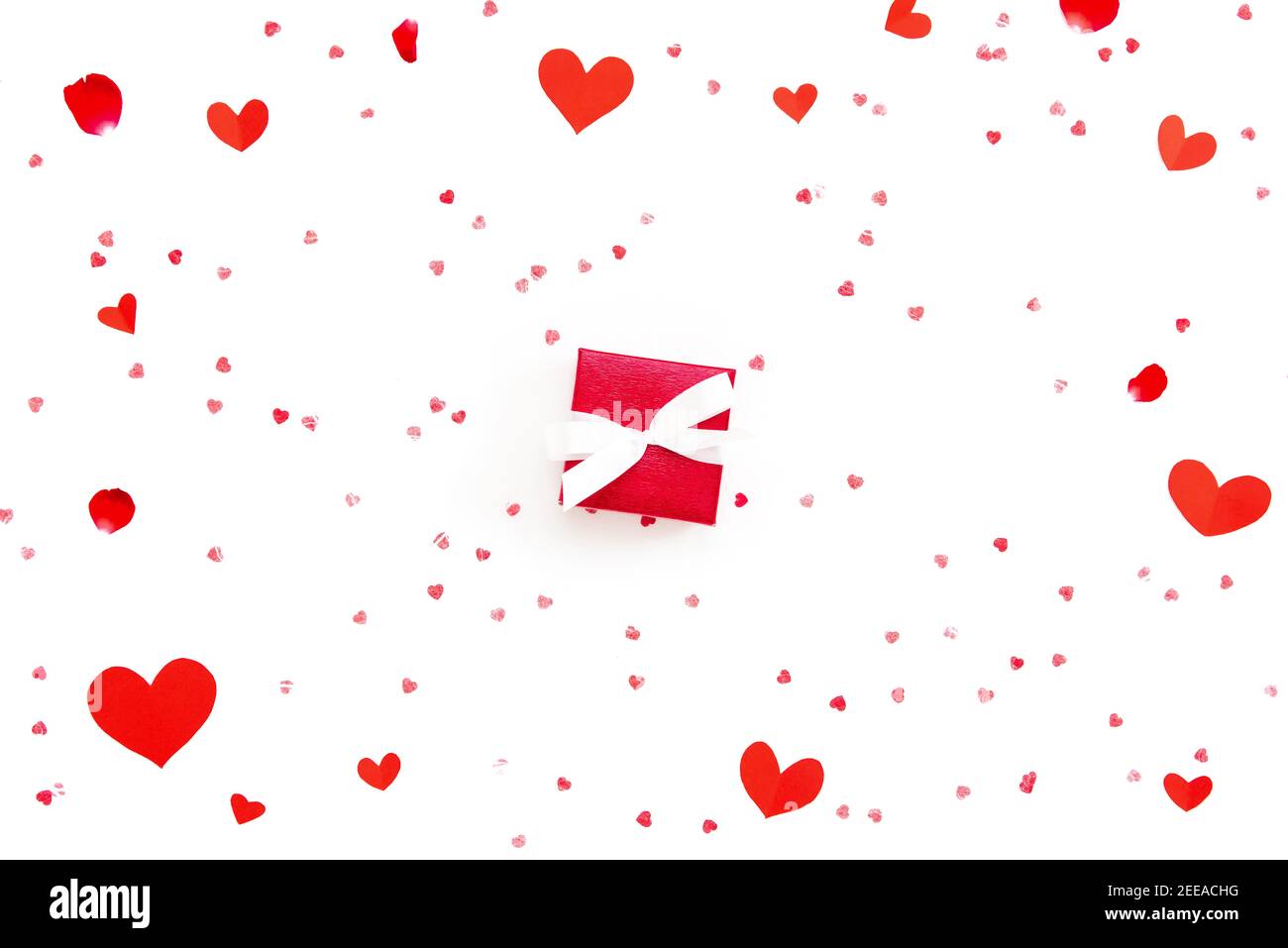 Petite boîte cadeau rouge de Saint-Valentin ou de mariage sur blanc arrière-plan en papier avec formes de coeur et pétales de rose Banque D'Images