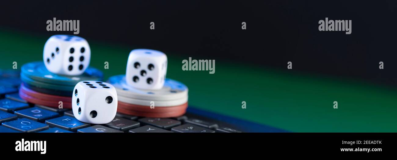 Plate-forme de jeu en ligne, casino et affaires de jeu. Casino dés et jetons sur le clavier de l'ordinateur portable sur fond vert. Banque D'Images