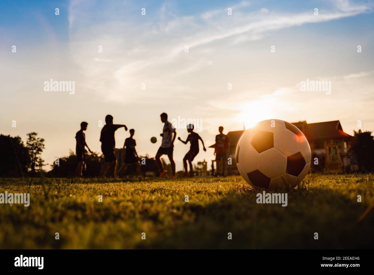 Sport d'action silhouette en plein air d'un groupe d'enfants qui s'amusent  à jouer au football pour s'exercer dans la zone rurale de la communauté  sous le crépuscule Photo Stock - Alamy