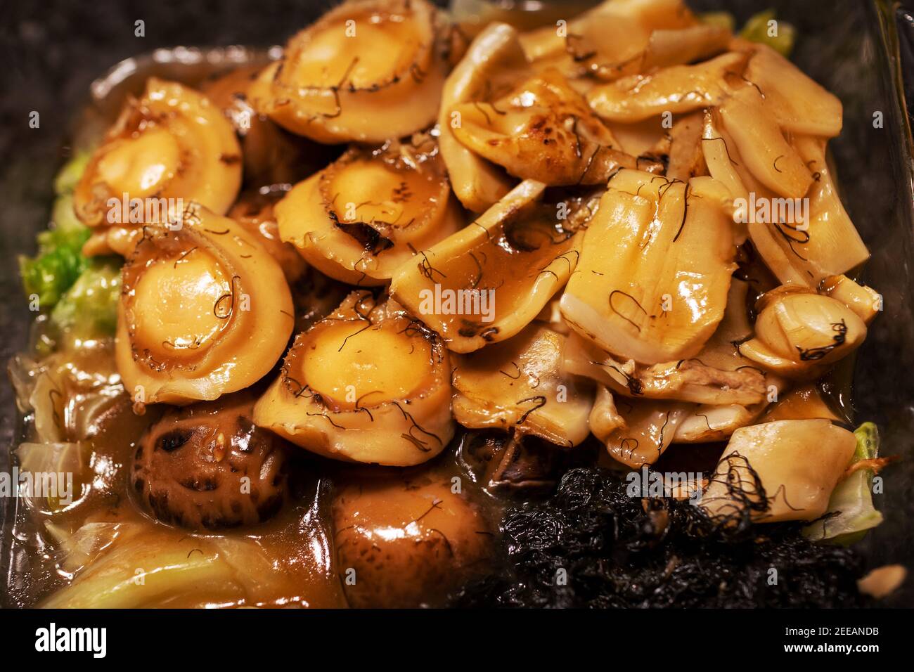 En gros plan de la cuisine chinoise traditionnelle du nouvel an, délicatesse de l'abalone braisée, de la maw de poisson, des légumes à cheveux ou de la graisse Choy et des champignons shiitake servis sur la laisse Banque D'Images